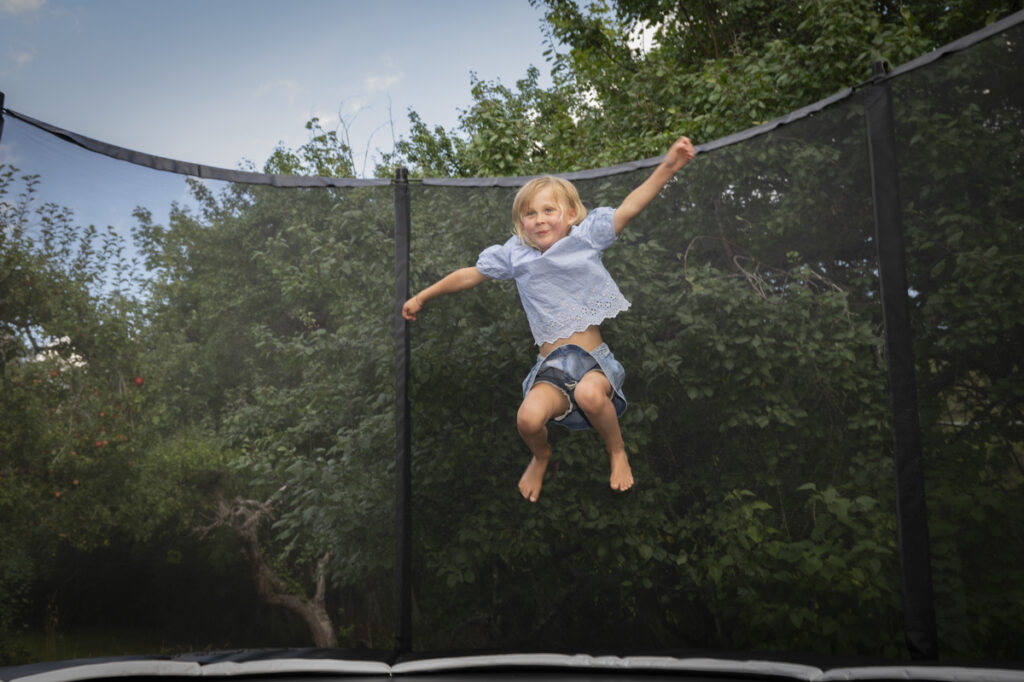 Barn hoppar och är glad på Orbit Stellar Oval studsmatta med skyddsnät.