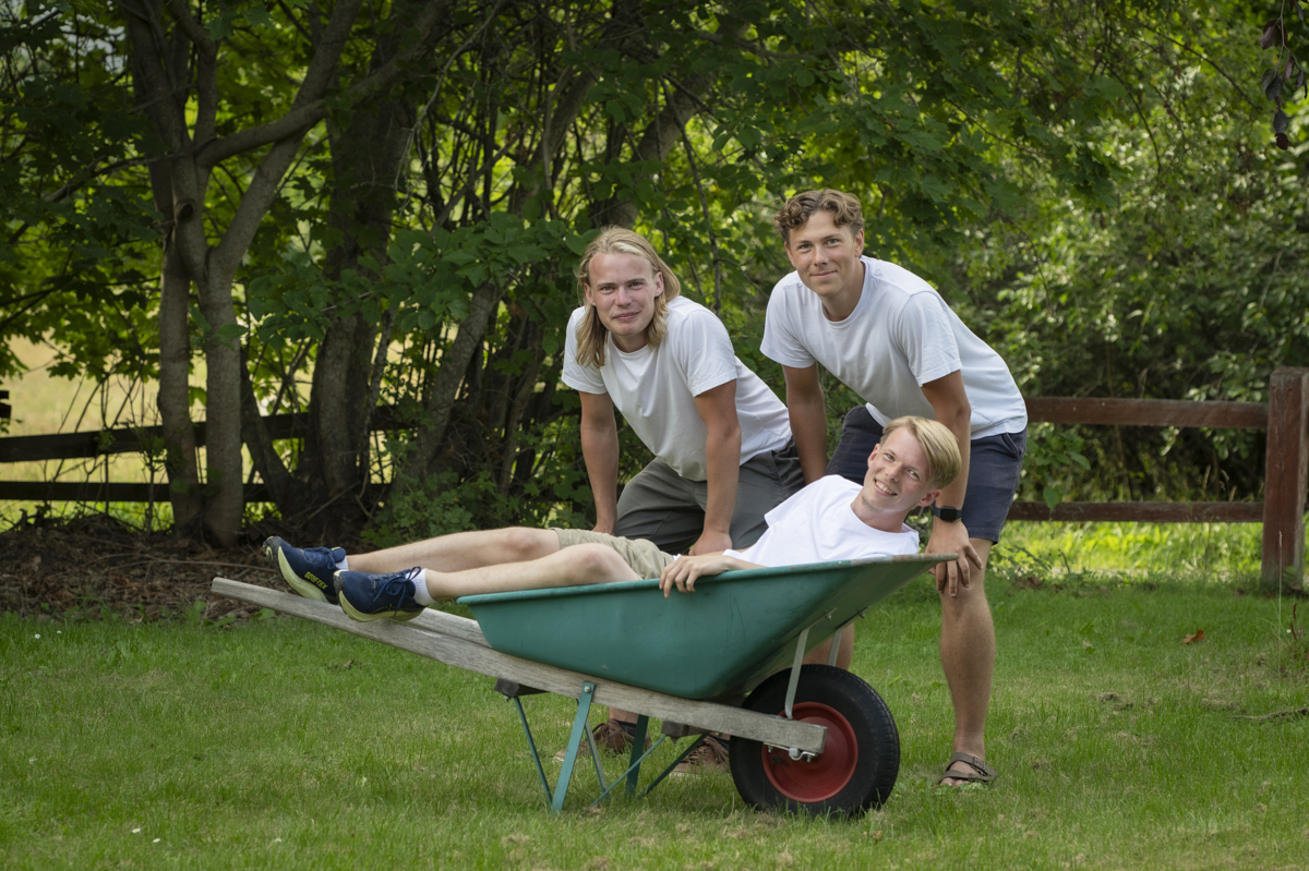 Teamet bakom Trampolinspecialisten visar arbetsglädje – två kollegor kör den tredje i en skottkärra.